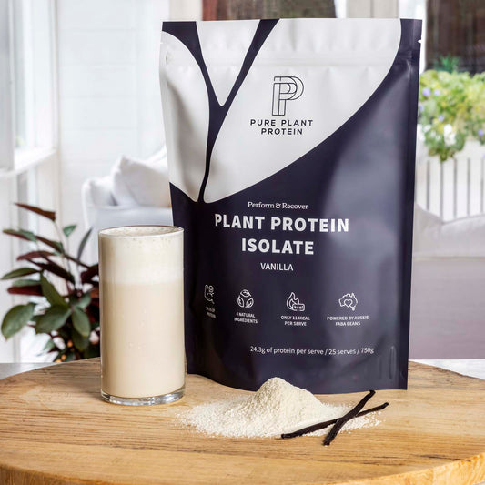 Pure Plant Protein plant protein isolate package with a glass of vanilla protein shake on a wooden surface.