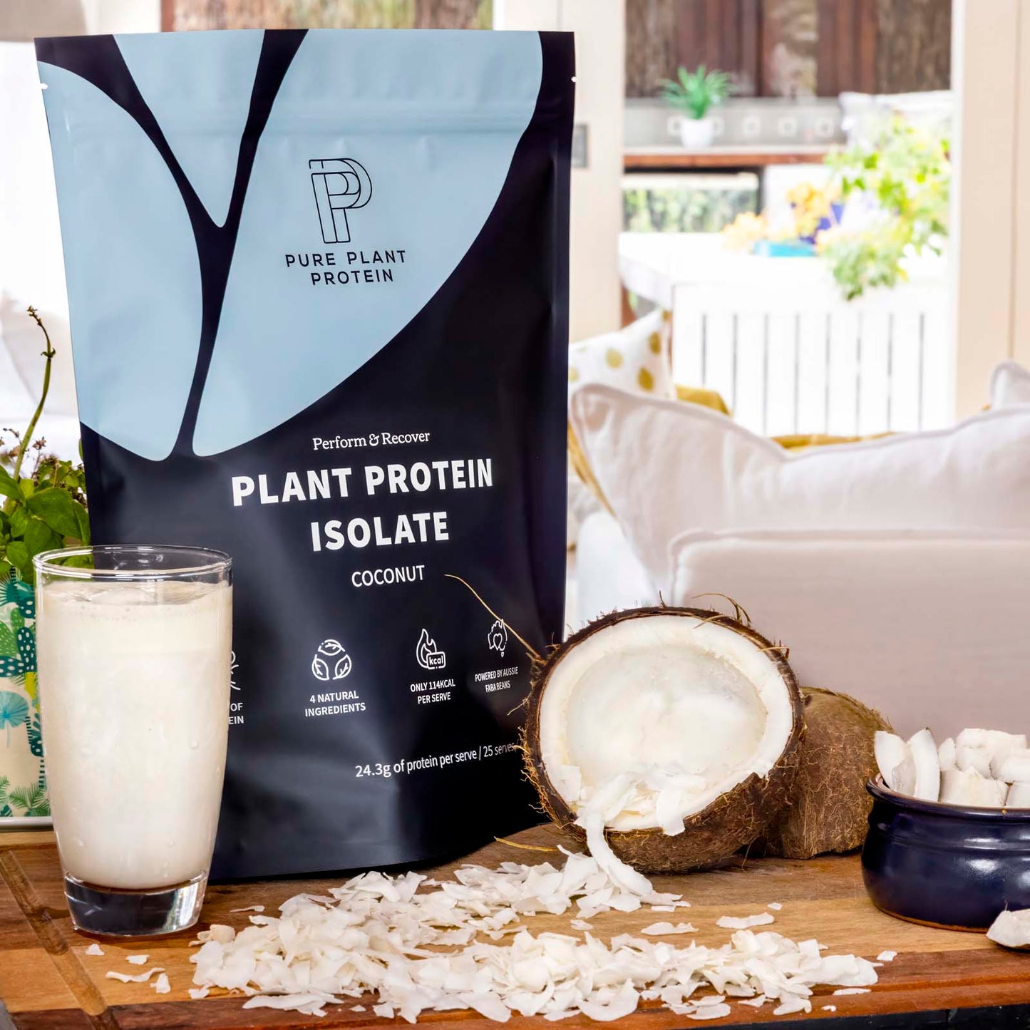 Pure Plant Protein coconut plant protein isolate package with a glass of protein shake and coconuts on a table.